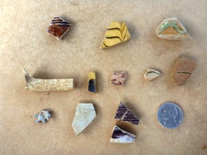 Early colonial artifacts of note recovered from the hot boxes include fragments of bulbous German Westerwald stoneware jugs with rilled necks colored with purple manganese pigment (bottom row, right), Midlands mottled from central England (top row left), dot and combed buff-bodied earthenware attributed to Staffordshire, England (top and middle row, center), small bits of sgraffitto (scratched decoration) red-bodied earthenware plates similar to vessels identified as originating from the town of Bideford in North Devon, England (middle row, right) and dipper white salt glazed stoneware also from England.           